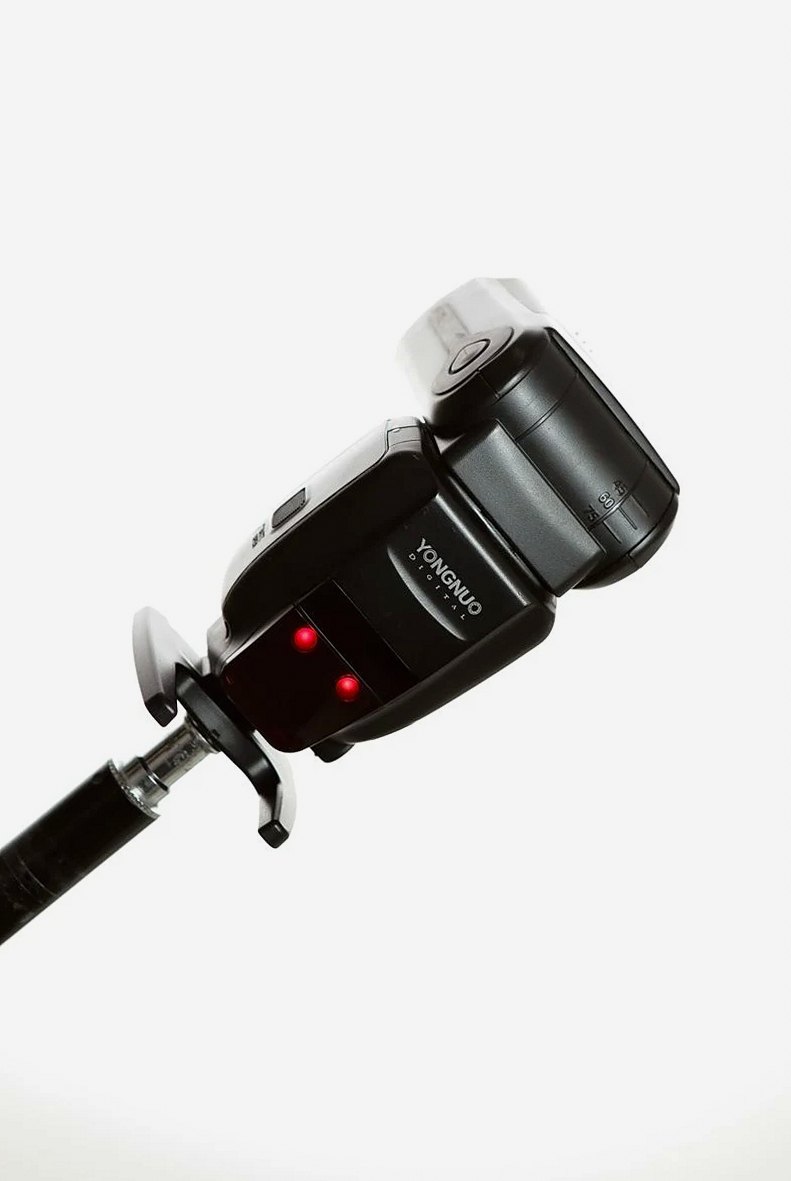 白い背景にスタンドで立てられたカメラフラッシュのクローズアップ。フォトグラファーに最適。